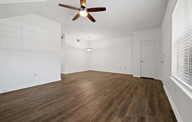 A room with a ceiling fan and wooden flooring.