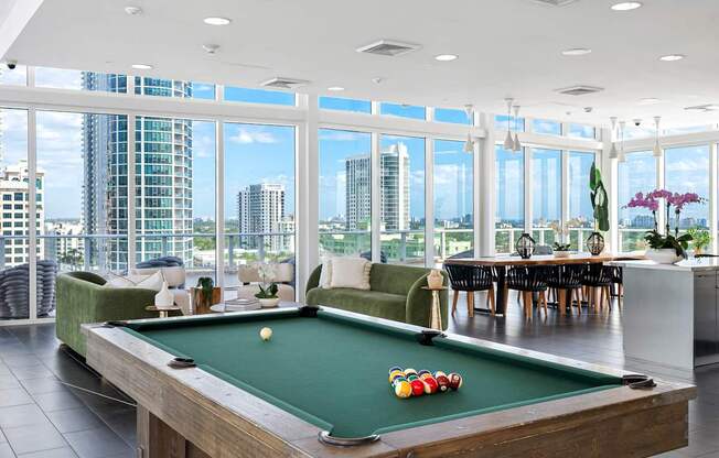 A pool table in a room with a view of the city.