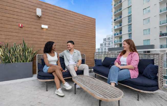 Three people are sitting on a bench and talking to each other.