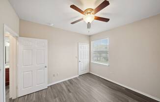 an empty bedroom with a ceiling fan and a window