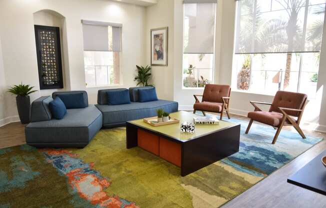 Clubhouse seating area with navy blue sofas and coffee table on colorful area rug in center of room