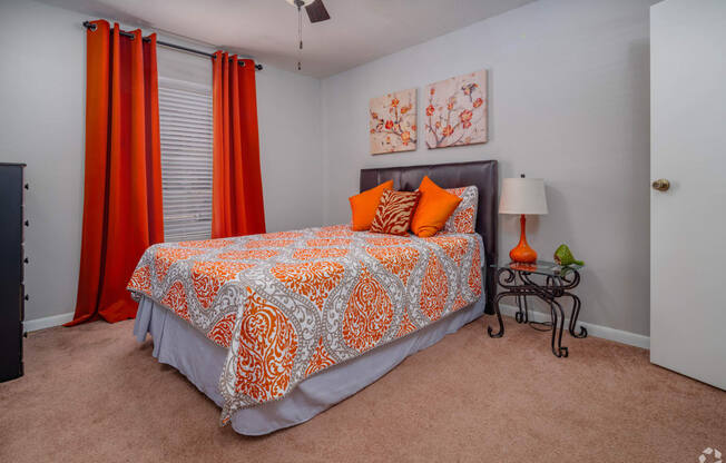 a bedroom with a bed and a window with orange curtains