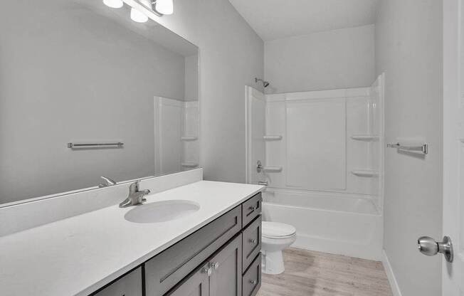 A white bathroom with a sink, mirror, and toilet.