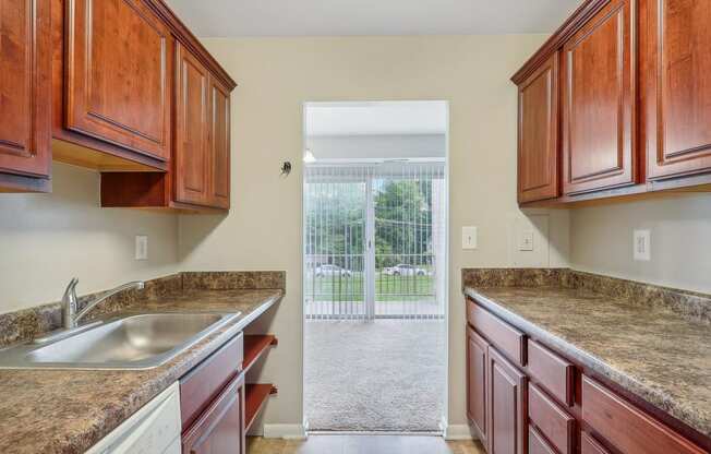 a kitchen with wooden cabinets and granite counter tops and a sliding glass door