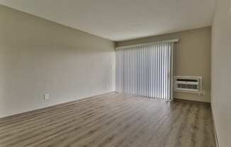 an empty living room with blinds and a window