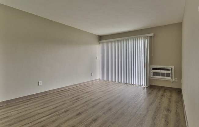 an empty living room with blinds and a window