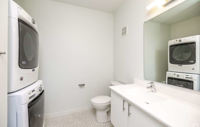 a washer and dryer in a bathroom with a toilet and a sink