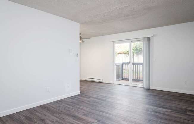 an empty living room with white walls and a sliding glass door