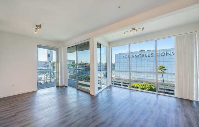 a living room with wood flooring and large windows and a balcony