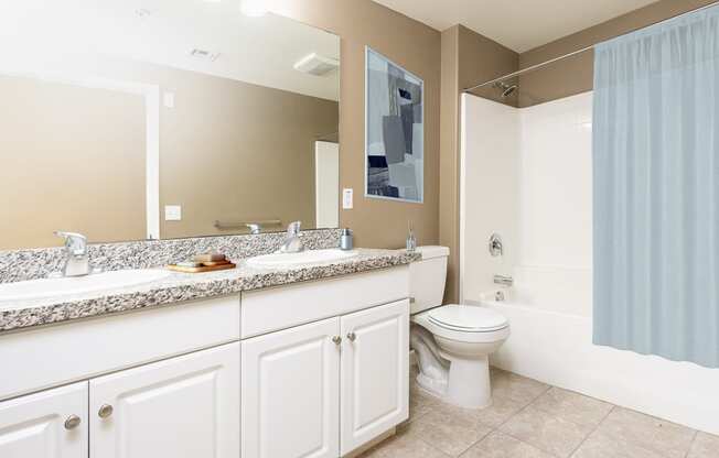a bathroom with white cabinets and a blue shower curtain