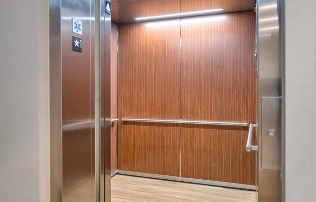 Silver elevator doors with a wooden panel inside.