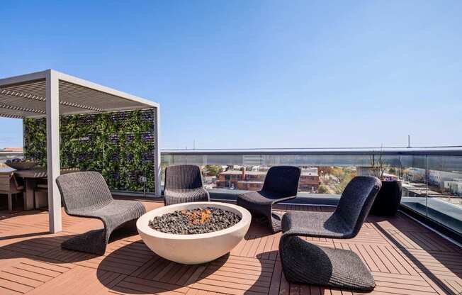 A patio with a fire pit and chairs.