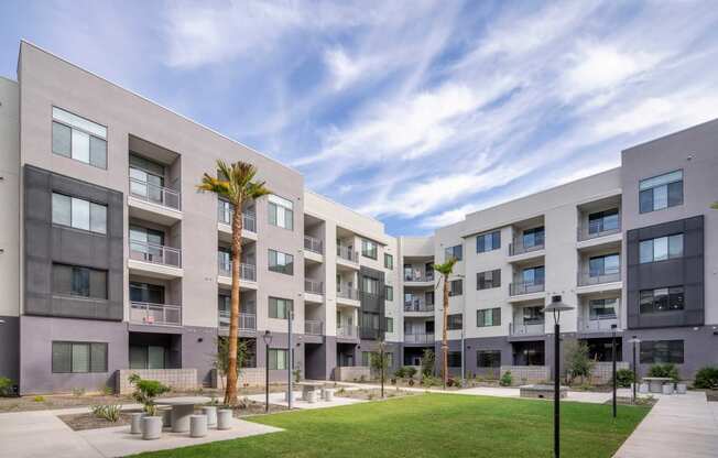 a group of apartment buildings with grass and palm trees