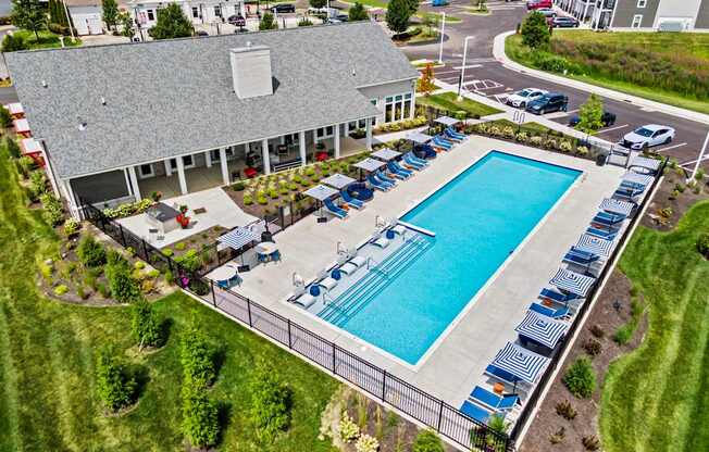 An aerial view of a pool surrounded by chairs and a building in the background.