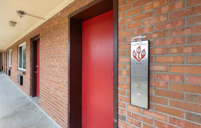 a red door with a sign on the side of a brick building