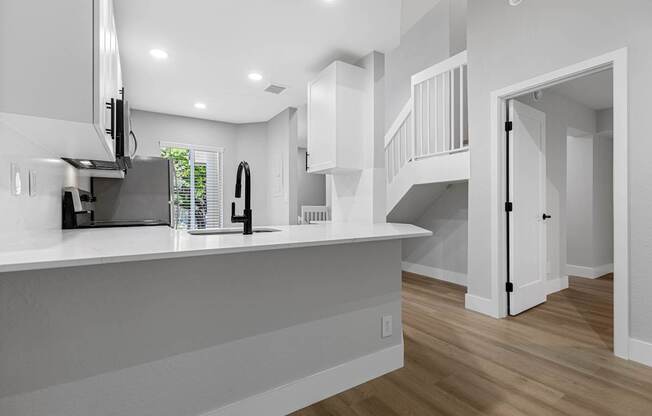 A modern kitchen with white cabinets and a wooden floor.