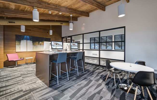 an open office space with tables and chairs and a bar with chairs at Ashford Belmar Apartments, Lakewood, CO 80226