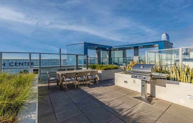 a patio with a barbecue grill and tables on a roof