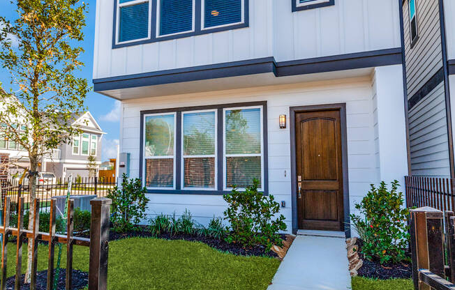 a white house with a wooden door and a sidewalk in front of it