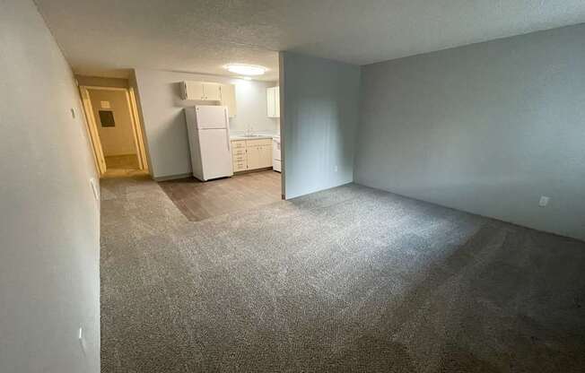 A room with a carpeted floor and a white refrigerator.