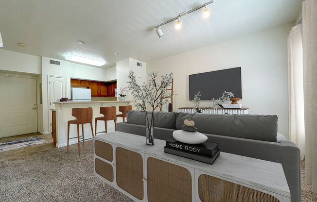 Liberty Commons Apartments, West Valley City, Utah, a living room with a couch, entryway storage, television, barstools and kitchen in the background.