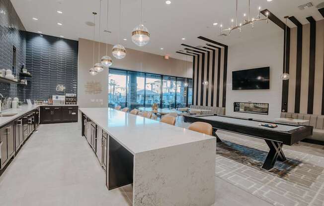 Modern luxury clubhouse with long kitchen bar, pool table, and seating.