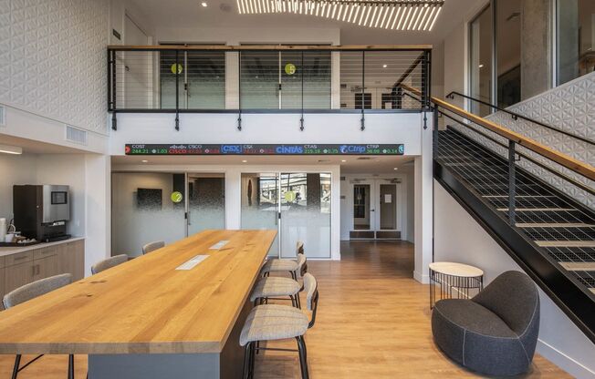 a communal table and chairs in a large room with stairs