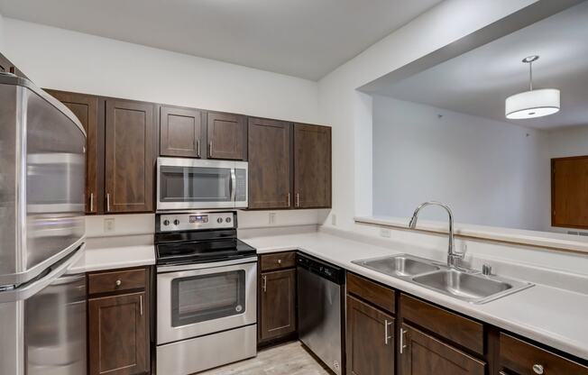 an empty kitchen with wooden cabinets and stainless steel appliances