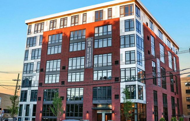 a large brick building with many windows and cars parked in front of it