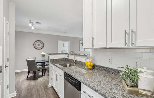 A kitchen with granite countertops and white cabinets.