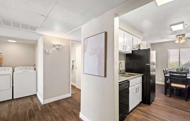 A kitchen with black appliances and wooden floors.
