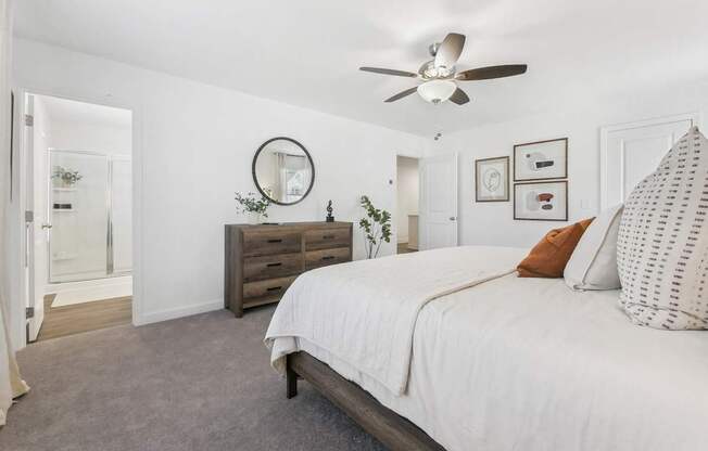 a white bedroom with a large bed and a ceiling fan