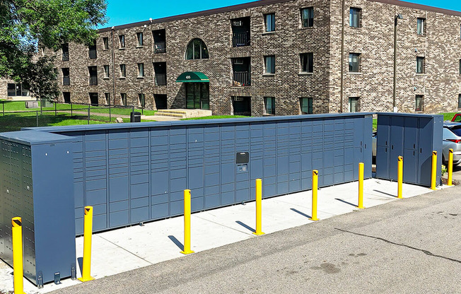 A building with a grey wall and yellow poles in front.