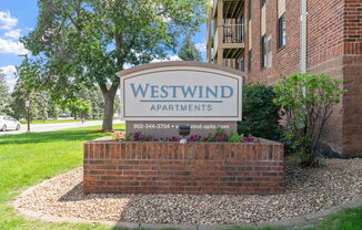 a sign for westwind apartments in front of a brick building