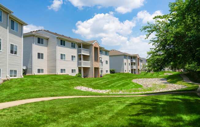 an apartment building with a green lawn and a sidewalk