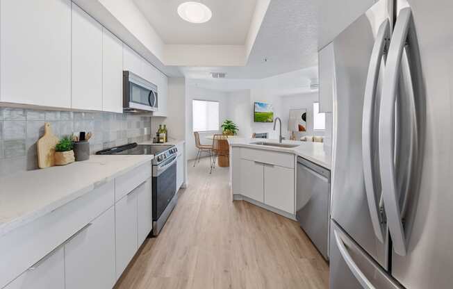 an open kitchen with white cabinets and stainless steel appliances
