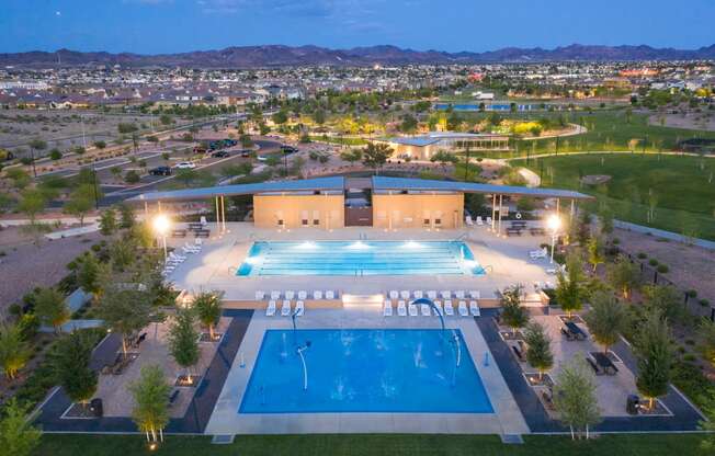an aerial view of the pool at night with the city in the background