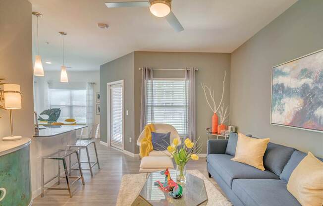 A living room with a grey couch and a yellow throw pillow.