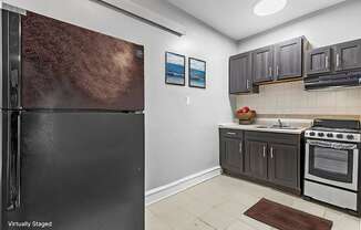 A kitchen with a black refrigerator and a stove top oven.