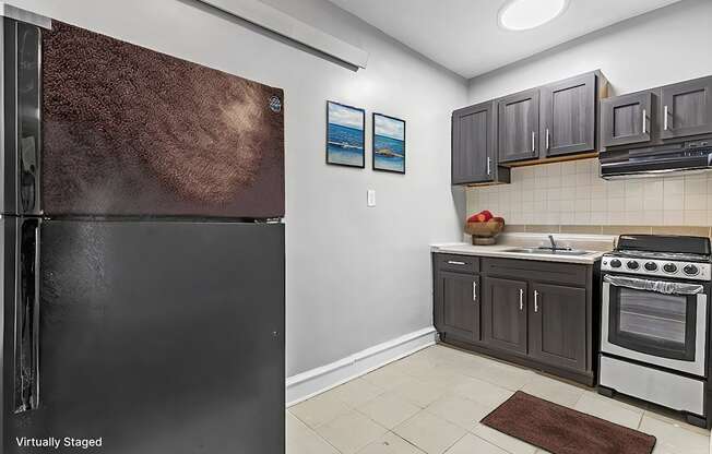 A kitchen with a black refrigerator and a stove top oven.