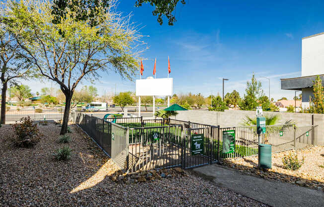 A white sign is on a gate in front of a green bush.
