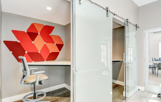 a room with a desk and a chair and a large red painting on the wall