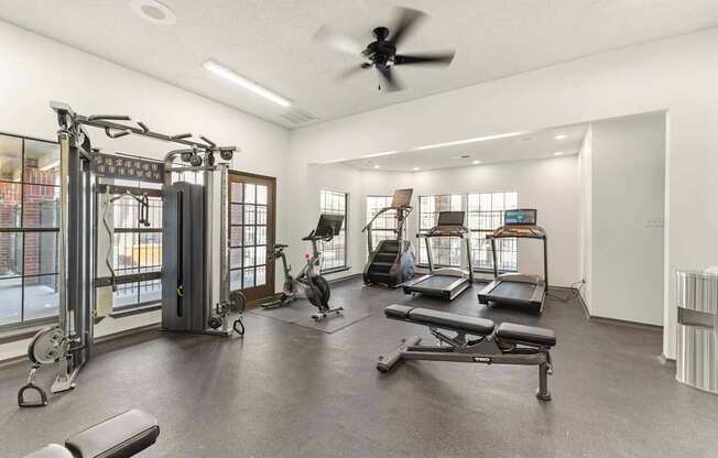 A spacious gym with a variety of equipment including treadmills, weights, and a rowing machine.