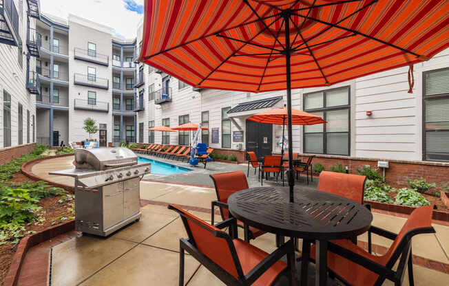 A patio with a table and chairs under an orange umbrella.
