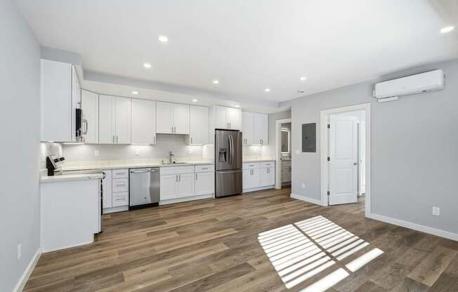 A kitchen with white cabinets and a wooden floor.