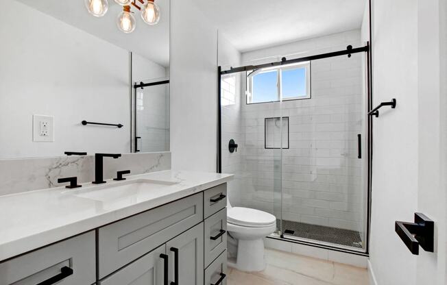 a white bathroom with a shower and a sink and a toilet