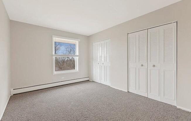 a bedroom with two closet doors and a window