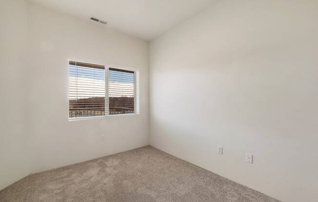 a bedroom with gray carpets, white walls and a sunny window with white blinds.at Shoreline Village, Richland