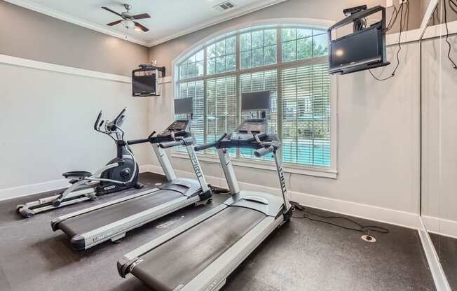 two treadmills and a tv in a room with a window