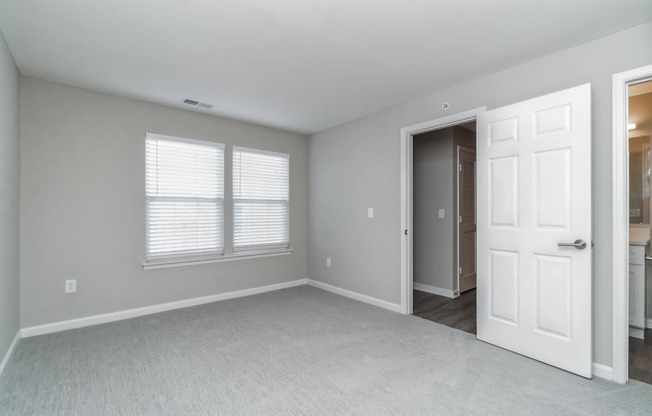 an empty bedroom with a white door and window